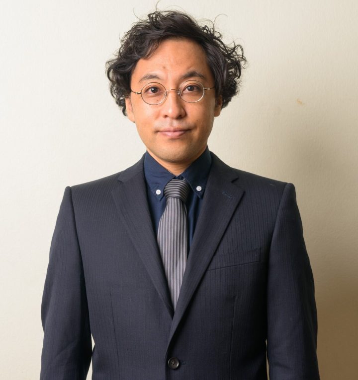 Studio shot of Japanese businessman in suit with curly hair against white background indoors